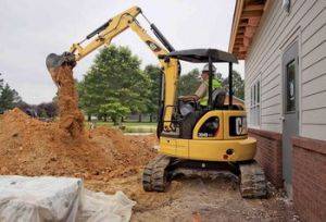 CAT 303 D mini Excavator working in tight space by house
