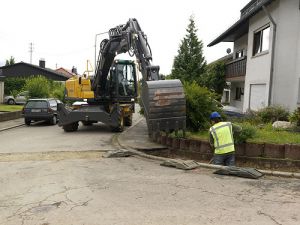 Wheeled Excavator working on road by house in tight space